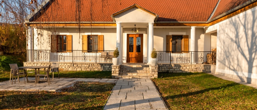 A kúria fehér falú, oszlopos tornácú főhomlokzata napfényben